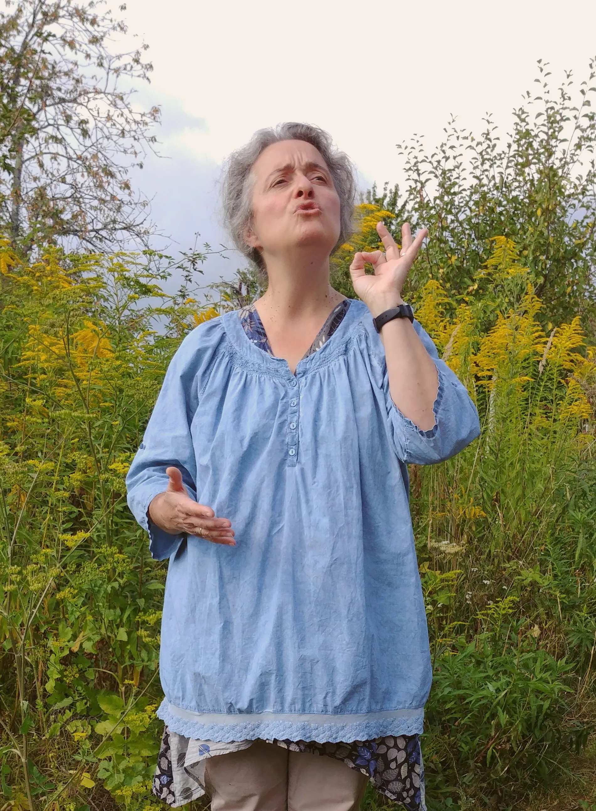 Anne en plein air, geste précis des doigts, parmi des fleurs jaunes