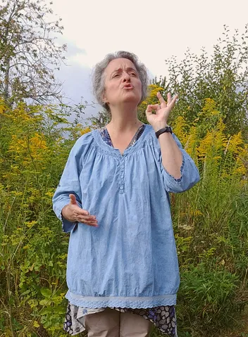 Anne en plein air, geste précis des doigts, parmi des fleurs jaunes