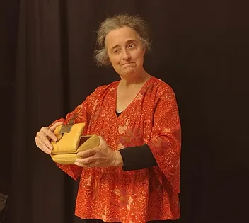 Anne en spectacle, expression dubitative, soulève le couvercle d'un coffret de bois