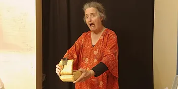 Anne en spectacle, expression d'effroi feint, un coffret de bois entre les mains
