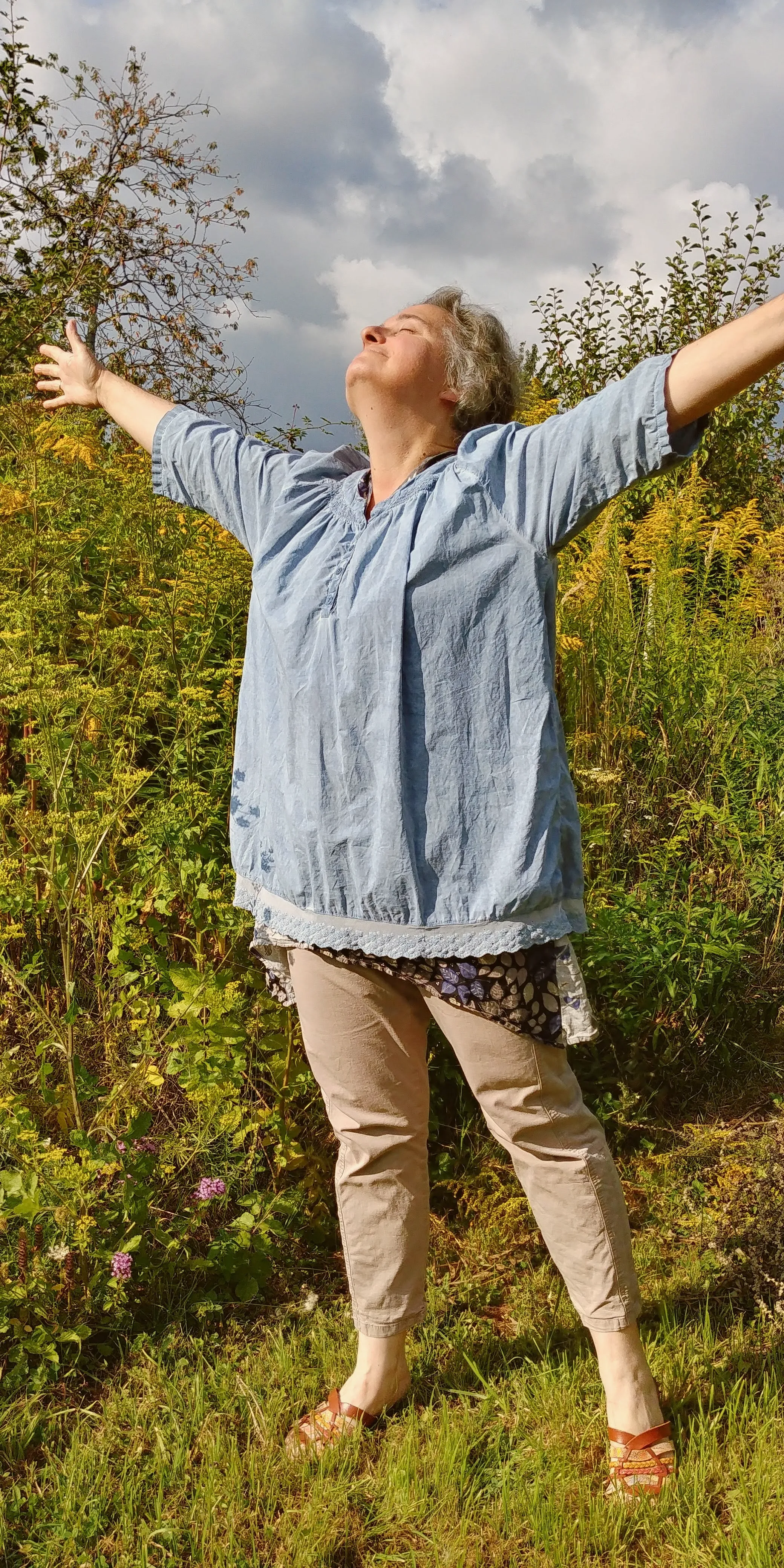 Anne, bras grands ouverts vers le ciel, dans un champ de fleurs sauvages