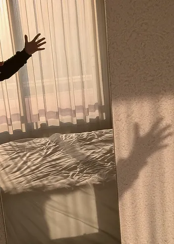 Jeu d'ombre et de lumière, une main et son ombre projetée à travers un voilage